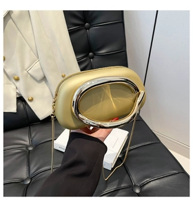 Detail of yellow oval crossbody bag with large metal ring handle on a casual suit background
