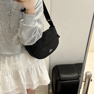 Minimalist black crescent canvas crossbody bag with adjustable strap and logo detail