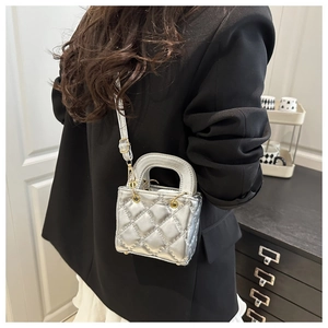 Detail of silver quilted leather mini crossbody bag featuring gold hardware and arc handle