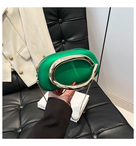 Detail of vibrant green box clutch bag with gold C-handle and metallic chain strap