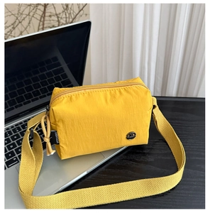 Détail du mini sac bandoulière en nylon jaune avec sangle tissée et logo métal