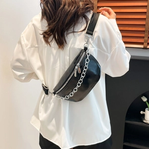 Glänzende schwarze Halbmond-Umhängetasche mit Silberkette und breitem Gurt am Model getragen