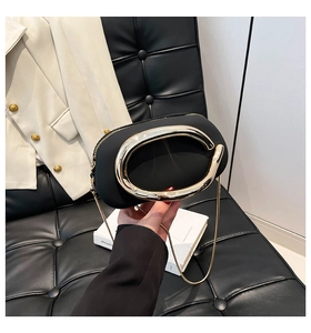 Close-up of black oval leather handbag featuring a bold gold metal ring handle