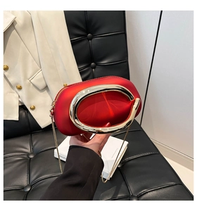 Detail of red satin round bag with large gold metal ring handle and chain strap