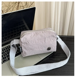 Vue rapprochée du tissu en nylon lilas froissé et de l'étiquette latérale du sac à bandoulière
