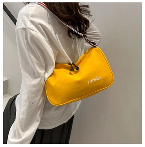 Gros plan d'un sac bandoulière jaune en nylon avec sangle rayée et double fermeture