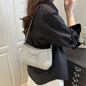 Silver sequin shoulder bag with metal bow detail worn by a model in a casual setting
