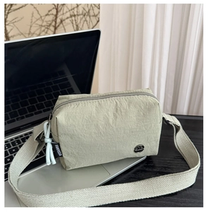 Détail du tissu en nylon texturé et de la large bandoulière du petit sac carré vert clair
