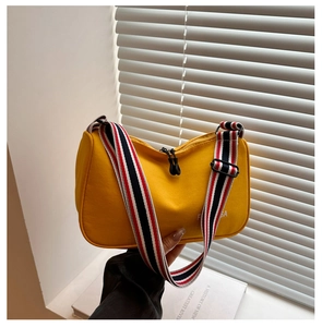 Détail du sac bandoulière en toile jaune avec large sangle tissée rayée et fermeture éclair