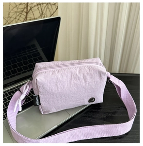 Détail du sac à bandoulière en nylon lilas montrant le tissu et l'étiquette tissée FANYISSA