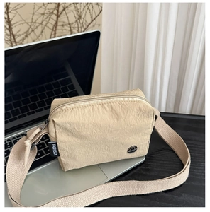 Détail d'un sac bandoulière en nylon kaki avec logo métallique et sangle réglable
