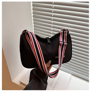Détail du sac hobo en nylon noir avec une large bandoulière rayée rouge blanche et bleue