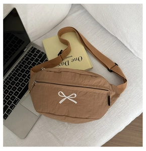Detailansicht der braunen Nylon-Gürteltasche mit Schleifenstickerei in gemütlicher Szene