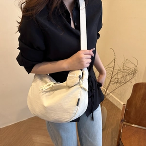Chic beige nylon crescent shoulder bag with round coin purse charm on a wide strap