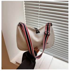 Détail du sac hobo blanc cassé avec une large bandoulière rayée rouge, bleue et blanche