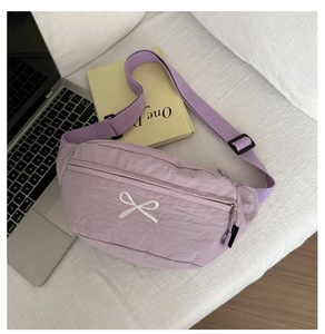 Detailansicht einer lila Nylon-Umhängetasche mit weißer Schleifenstickerei und Gurtband