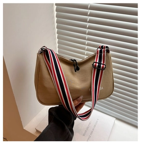 Détail du sac bandoulière en toile kaki avec sangle rayée et logo de cheval imprimé