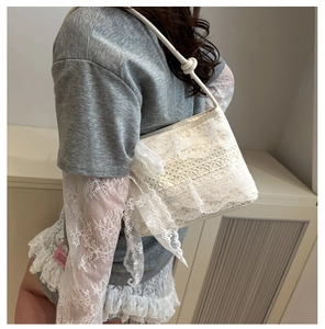 Dettaglio della borsa a spalla in pizzo bianco con fiocco decorativo e trama a balze