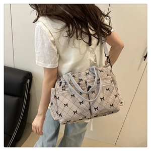 Detail of beige canvas tote bag with black bow print, side pockets and adjustable strap