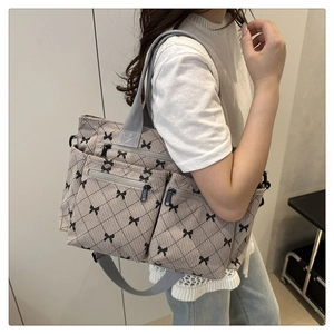 Detail of beige corduroy tote bag featuring black bow patterns and quilted diamond stitching