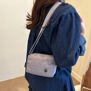 Sac bandoulière en nylon violet clair avec large sangle, porté par un mannequin