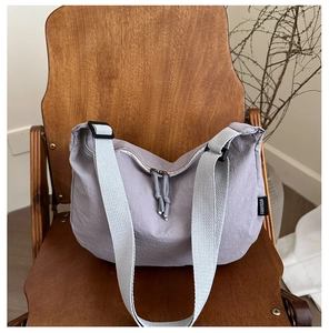 Detail of light purple nylon crossbody bag with wide strap and branded woven label