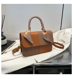 Detail view of woven leather handbag with checkered scarf wrapped around the top handle