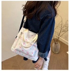 Detail of floral tote bag showing side zipper pocket and durable webbing handle