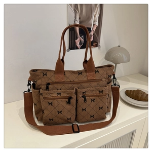 Detail of dark brown corduroy tote bag featuring black bow prints and functional pockets