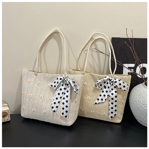 Detail of straw tote bags with daisy embroidery and polka dot ribbon on black table