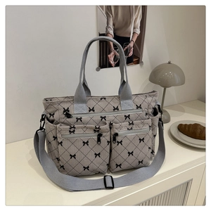 Detail of grey corduroy tote bag featuring bow patterns and front zipper pockets