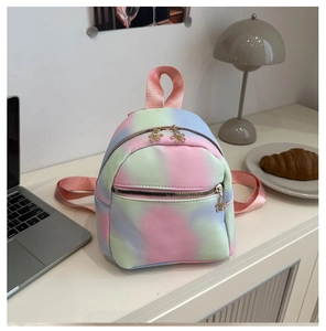 Close-up of pastel tie-dye mini backpack with unique gold flower zipper pulls on a white desk