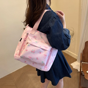 Pink floral tote bag with rose patterns and ribbon bows shown on a model's shoulder