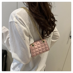 Close-up of pink quilted chain bag with gold metal straps worn by a model from the back