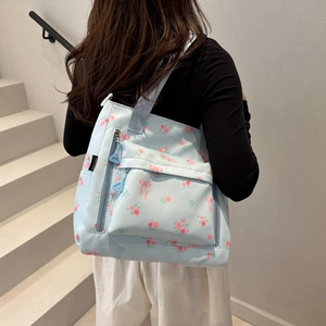 Light blue floral tote bag with pink rose patterns worn by a model on stairs