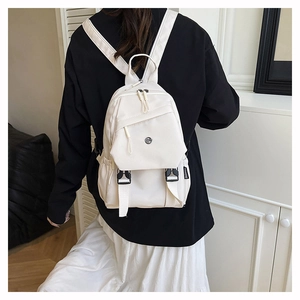 Detail of white nylon backpack featuring fashion tag and adjustable buckle straps