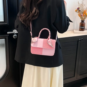 Pink patchwork square handbag with silk scarf handle detail worn by a model in a black blazer