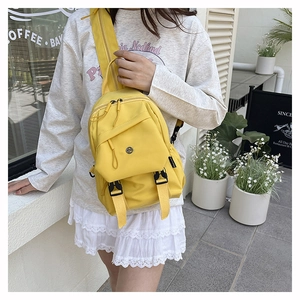 Close-up of bright yellow nylon mini backpack with adjustable buckles and metal logo