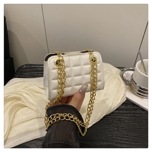 Detail of white quilted crossbody bag with luxury gold chain straps and lattice texture