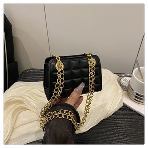 Detailed macro view of black quilted leather texture and premium gold chain strap on handbag