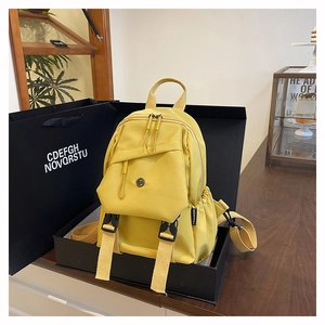 Detail of yellow nylon backpack featuring functional buckle pockets and fashion label