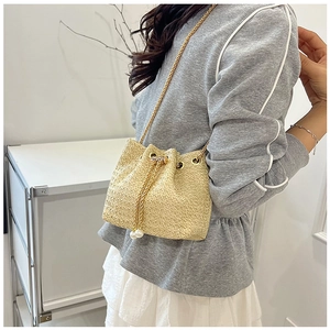 Detail of straw bucket bag with large pearl drawstring accents and gold chain strap