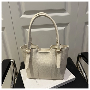 Detail of cream lychee grain leather handbag with pale gold metal buckle and handle