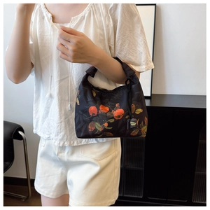 Detail of black tote bag with traditional Chinese persimmon print on model