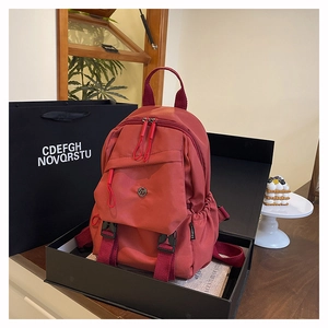 Brick red nylon backpack inside an elegant gift box with luxury aesthetic packaging