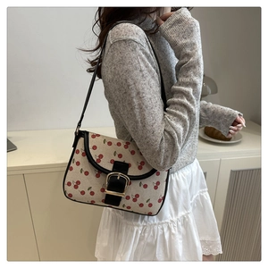 Detail of cute cherry print shoulder bag with black leather trim and gold buckle