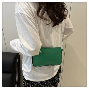 Close-up of green chain strap handbag with silver bead trim and embossed leather texture