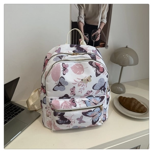 Close-up of white floral backpack featuring colorful butterfly patterns in a lifestyle setting