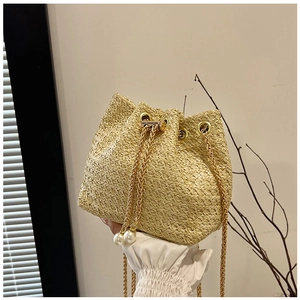 Detail of straw bucket bag featuring fine weave texture and elegant pearl drawstring tassels