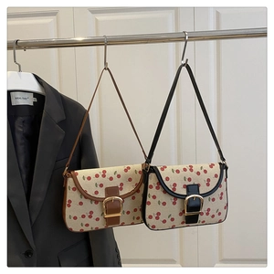 Close-up of cherry print baguette bags with gold buckles hanging in a home setting
